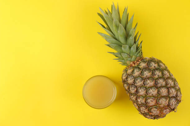 istock Large ripe fruit pineapple and pineapple juice on a bright yellow background. summer. top view. 1324421932