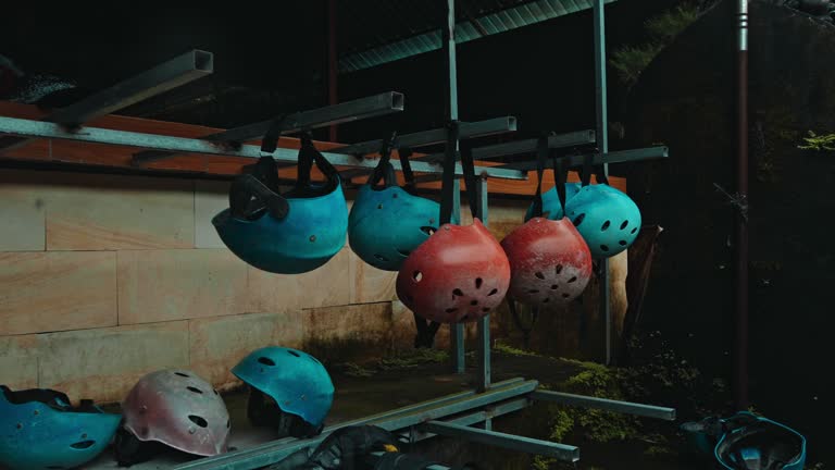 Black protective jackets with yellow lines and protective helmets to practice rafting hanging on a wall