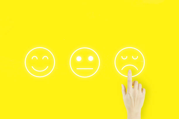 istock Customer service evaluation concept. Young woman's hand finger pointing with hologram face emotion on yellow background. Customer Experience Concept. 1324422849