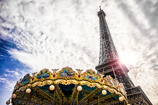 Eiffel tower with a merry go round and cloudy sky