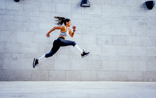 Young caucasian woman athlete jumping during exercising outdoor