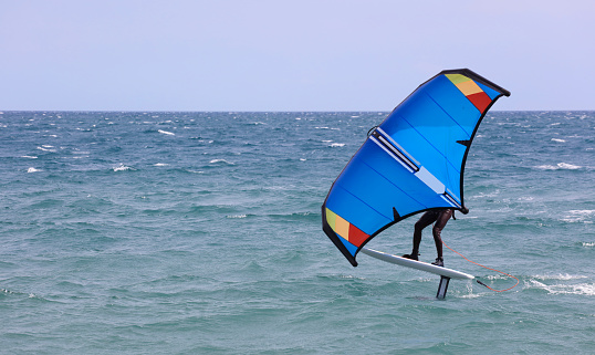 Athletic man having fun while kitesurfing on the sea. Copy space.