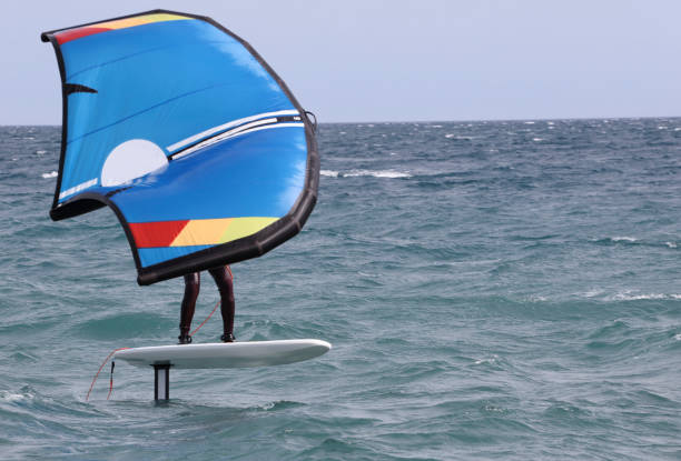 istock surfer in windfoil sailing through the waves. 1324440043