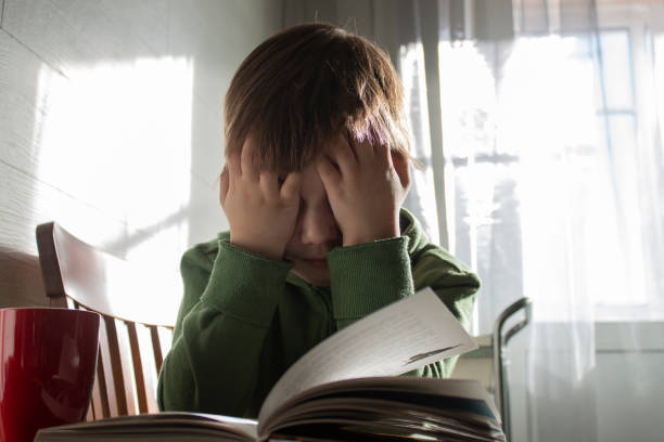istock Cute boy reading a book at home 1324444822