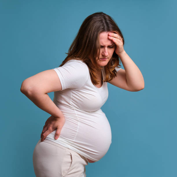 istock Pregnant woman health problems, studio shot on blue background 1324447374