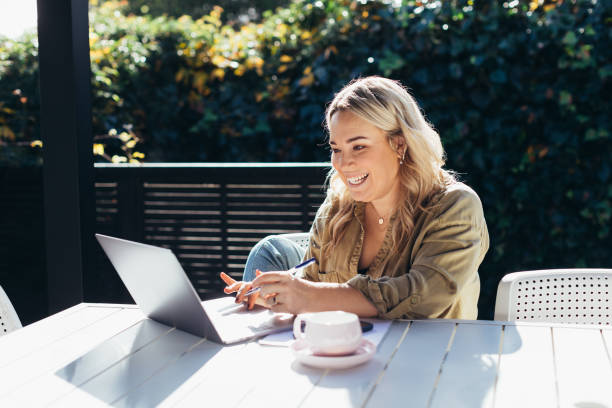 istock Woman sitting outside working on laptop 1324447401
