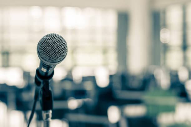 haut-parleur vocal de microphone dans un séminaire d’affaires, une présentation vocale, une assemblée publique, une salle de conférence ou une salle de conférence dans un événement corporatif ou communautaire pour une audience publique d’accueil - human settlement audio photos et images de collection