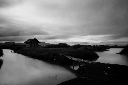 a black and white landscape of a traditional house in the midle of lake using the long exposed technique in banten Indonesia
