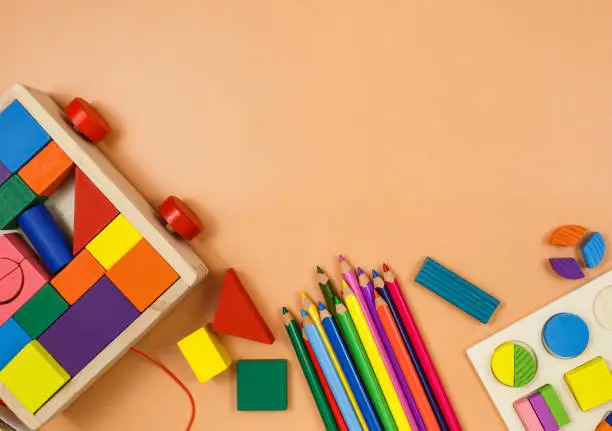 Photo of Colorful cubes, paints, pencils, blocks, modeling clay on orange background. Interesting math, games for preschool for kids. Education, back to school concept