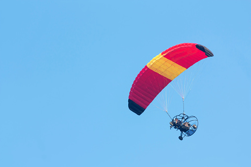 A paraglider with a motor on a sky background