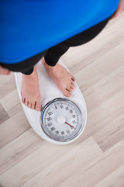 istock Woman Measuring Weight On Weighing Scale 1324470714