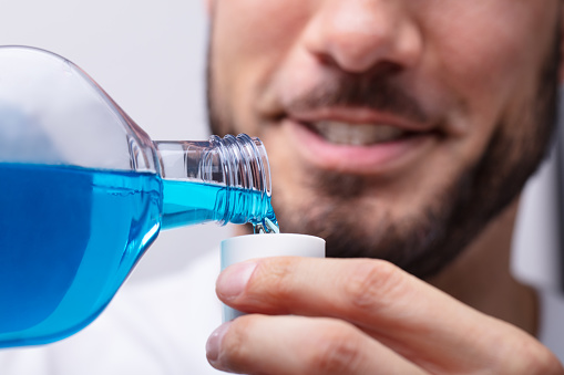 Close-up Of A Man's Hand Pouring Mouthwash Into Cap