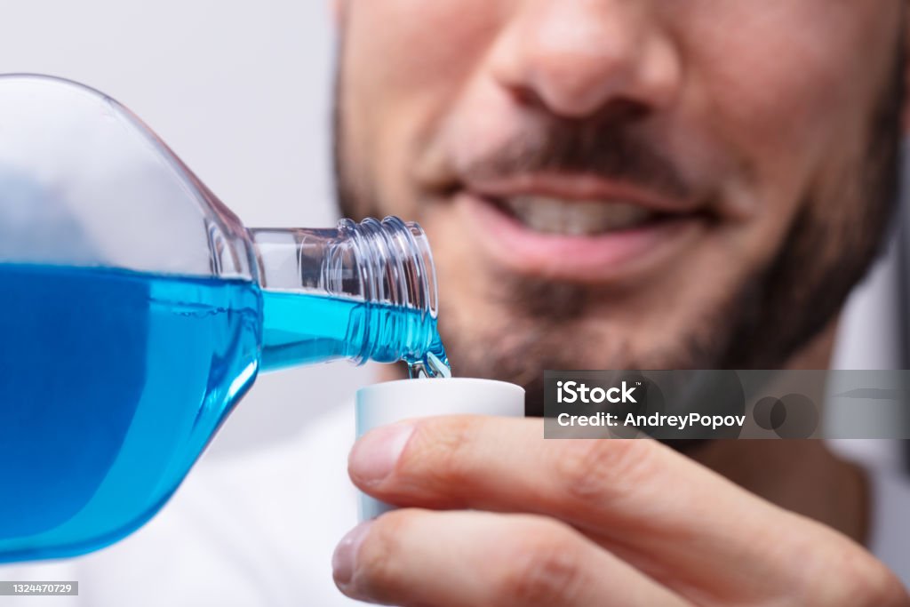 Man Pouring Mouthwash In To Cap Close-up Of A Man's Hand Pouring Mouthwash Into Cap Mouthwash Stock Photo