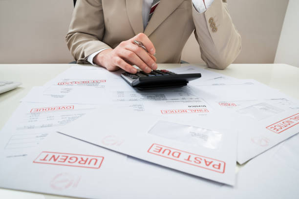 Businessman With Calculator And Unpaid Bills