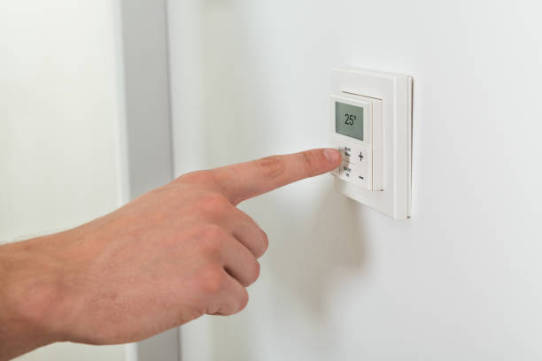 istock Person Hands Adjusting Temperature On A Digital Thermostat 1324471844