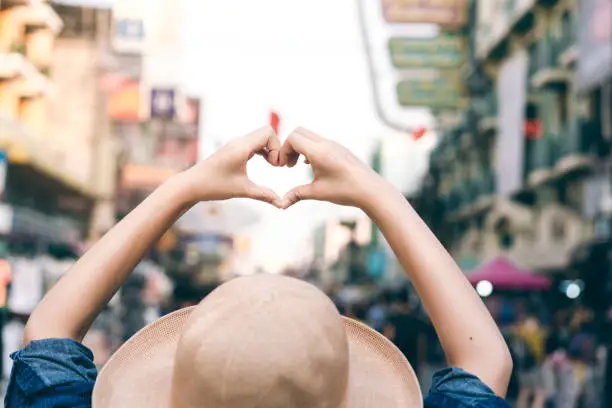 Photo of Asian traveller woman hand with heart gesture for love.