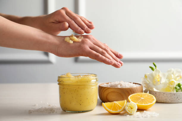 mujer aplicando exfoliante corporal a mano en la mesa de madera, primer plano - exfoliacion fotografías e imágenes de stock