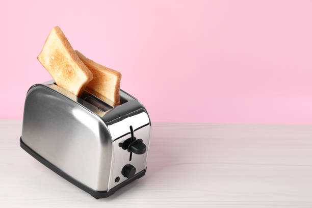istock Modern toaster with slices of bread on white wooden table. Space for text 1324478739