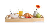 Wooden tray with delicious breakfast and beautiful flower on white background