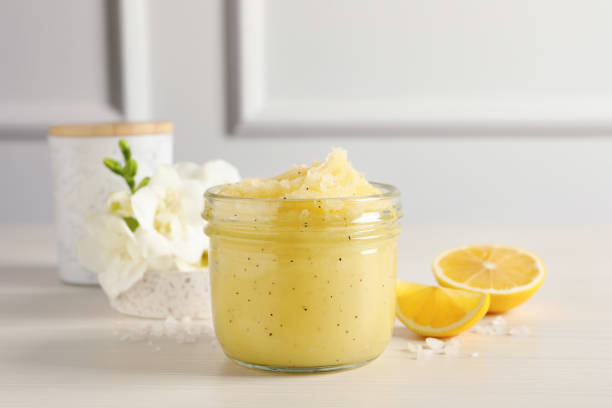 Body scrub in glass jar, freesia flowers and lemon on wooden table Body scrub in glass jar, freesia flowers and lemon on wooden table exfoliation stock pictures, royalty-free photos & images