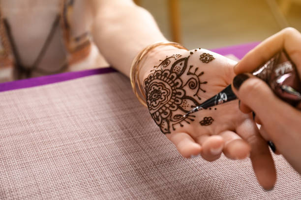 istock Professional mehndi master making henna tattoo at table, closeup. Space for text 1324484932