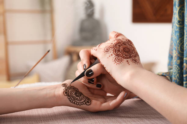 istock Professional mehndi master making henna tattoo indoors, closeup 1324486768