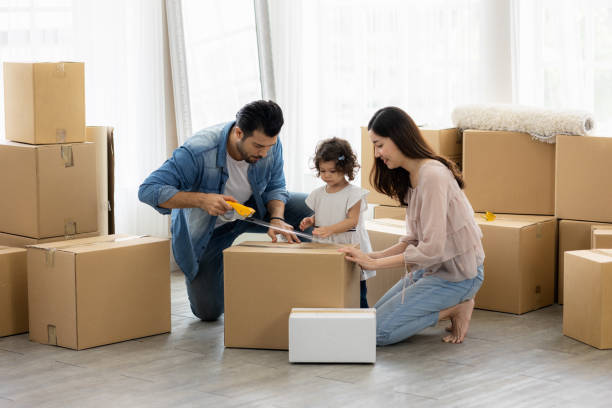 la famille vient d’acheter de nouveaux meubles et a aidé à organiser la maison. mon père et sa fille viennent de déménager dans une nouvelle maison. ils déballent la boîte à colis et s’arrangent sur le sol dans le salon. - activité physique photos et images de collection