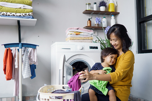 mother a housewife with a baby engaged in laundry with washing machine