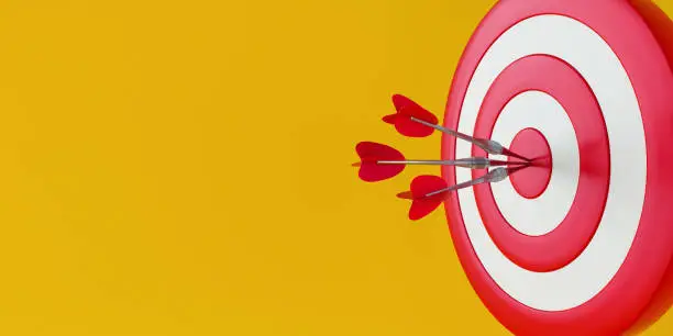 Photo of Close up red dart hitting target on yellow background.