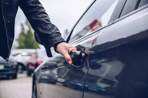 Man is reaching for the car door handle. Car rental or car theft concept