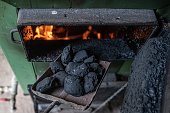 Pieces of coal on dirty shovel . Adding to the stove.