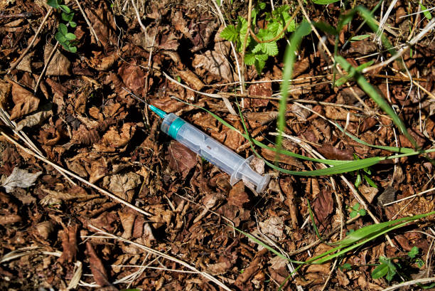 Used disposable syringe is lying on the ground stock photo