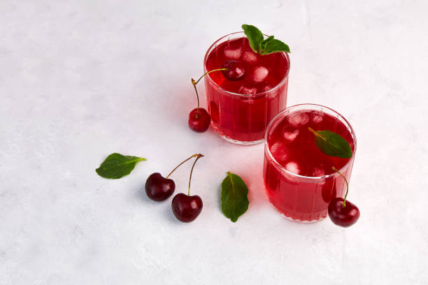 istock Cherry cocktail with ice and mint on a light grey background. 1324502888