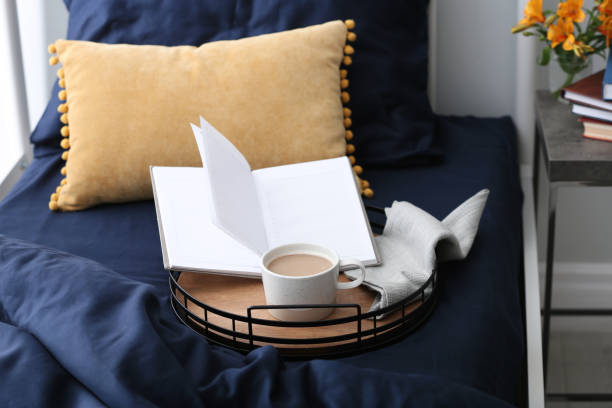 istock Cup of coffee and notebook on bed with fresh linens indoors 1324505350