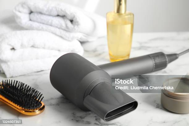 Hair Care Products Dryer And Brush On White Marble Table Stock Photo - Download Image Now