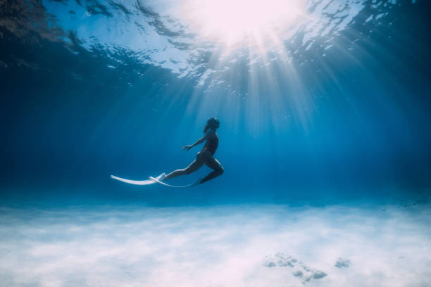Freediver with white fins glides and posing underwater in ocean with sunlight. Freediver with white fins glides and posing underwater in ocean with sunlight. cancun photos stock pictures, royalty-free photos & images