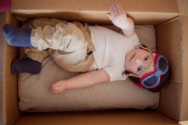 The boy in the pilot's hat inside the cardboard box