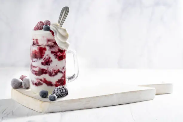 Photo of Raspberries yogurt smoothie overflow with frozen berries