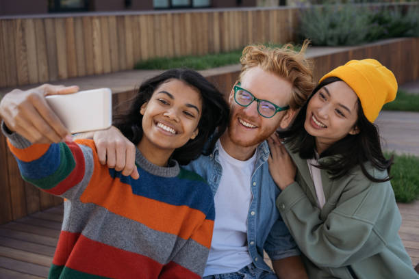 istock Multiracial people using mobile phone taking selfies, smiling outdoors. African American woman influencer streaming video with happy friends. Positive lifestyle concept 1324510840