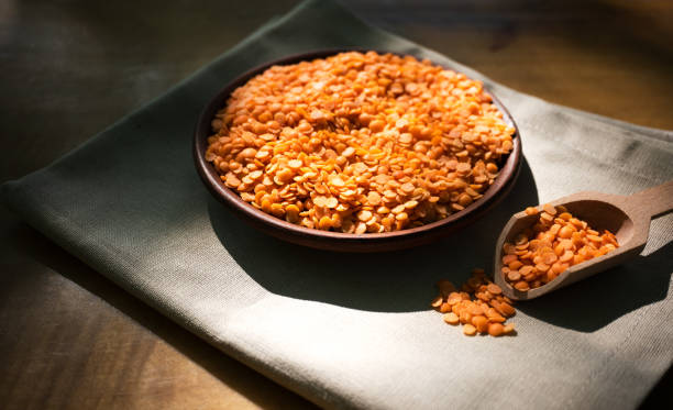 istock Red lentils in a clay plate on a wooden table. 1324513555
