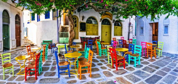 traditional greek taverns on the streets. ios island, old town chora. restaurant with colorful typical chairs. cyclades, greece - greek culture bar restaurant greece imagens e fotografias de stock