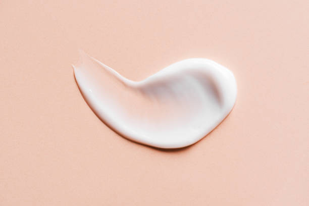 Cosmetic cream drop texture smudged Cosmetic cream drop texture smudged on nude or beige background, top view. White swatch of skin care product on nude surface. color swatch photos stock pictures, royalty-free photos & images