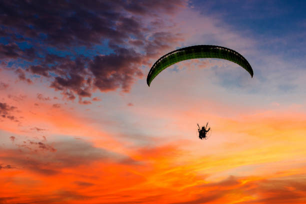 paysage de coucher de soleil parachutiste volant en douceur. silhouette volante para-motrice avec coucher de soleil. silhouette de parapente volant dans le ciel du soir avec coucher de soleil. - action adventure aerospace industry air vehicle photos et images de collection