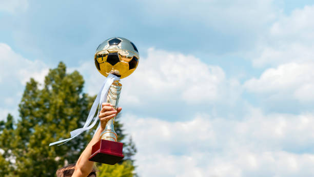 soccer tournament trophy golden football ball in hands of child. young soccer player holding champion trophy cup. award and celebration victory in kids football championship - dream time imagens e fotografias de stock