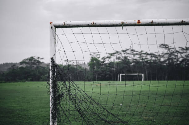 istock Goalposts on a football field with a broken net 1324519545