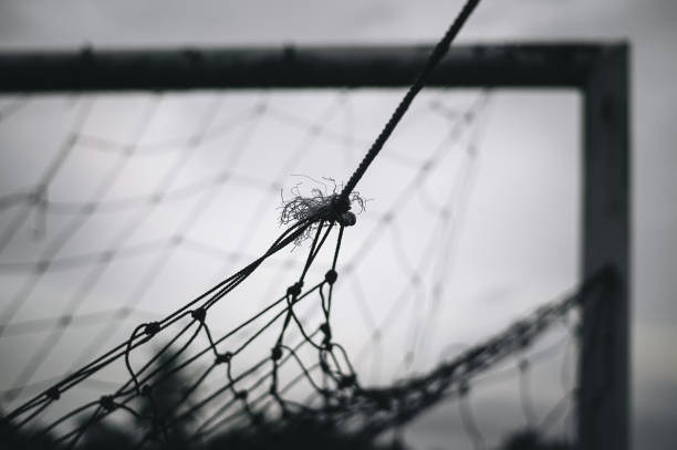 istock Goalposts on a football field with a broken net 1324519622