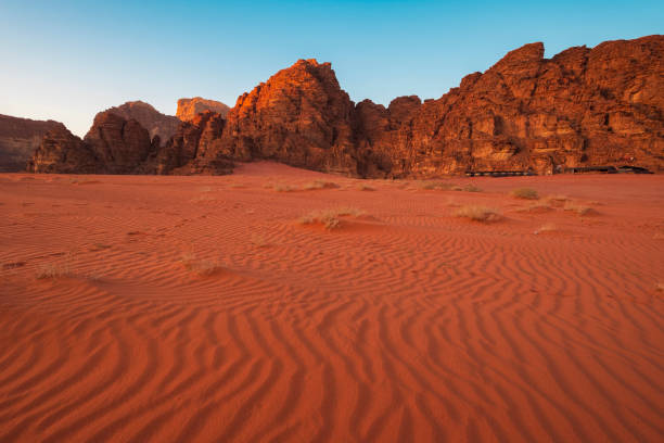 砂の上にパターンを持つヨルダンのワディラムの赤い砂漠の夕日に岩のそばのテントキャンプ - wadi rum ストックフォトと画像