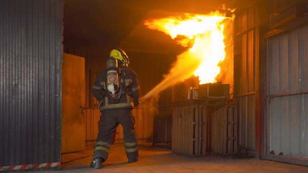 istock A firefighter or fireman with uniform using water fire hose against hot burning fire and dangerous smoke in the container, an emergency accident rescue. People. Hero 1324526183