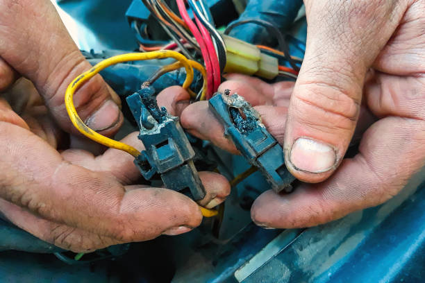 cortocircuito en coche. electricista masculino sosteniendo un cable carbonizado. reparación de vehículos, estación de servicio de automóviles - cable car fotografías e imágenes de stock