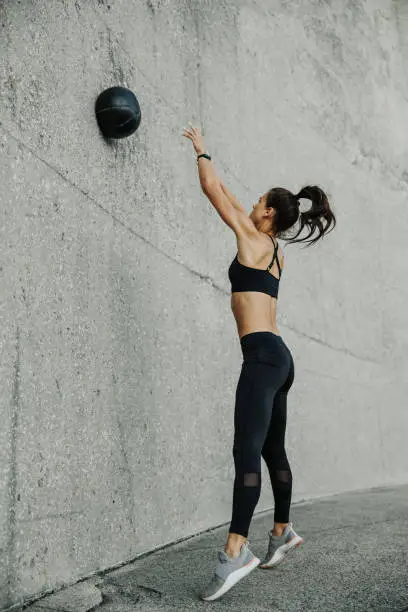 Female athlete exercising with a medicine ball. Woman in fitness wear doing workout using a medicine ball.
